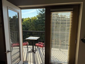 A balcony with a table and chairs, a view of trees, and a door with a glass panel. - Updated Pigeon Forge Condo.  3BDR 2BA W/ 2 Pools on the Parkway (Pigeon Forge)