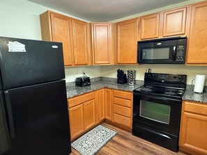 A kitchen with wooden cabinets, a black refrigerator, a microwave, a stove, and a toaster. - Updated Pigeon Forge Condo.  3BDR 2BA W/ 2 Pools on the Parkway (Pigeon Forge)