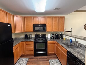 A kitchen with wooden cabinets, a black refrigerator, a microwave, a stove, and a dishwasher. - Updated Pigeon Forge Condo.  3BDR 2BA W/ 2 Pools on the Parkway (Pigeon Forge)