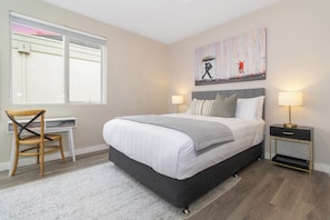A bedroom with a bed, bedside tables, a chair, a desk, a window, and a painting on the wall. - Corner Penthouse with City Views in Armadale (Armadale)