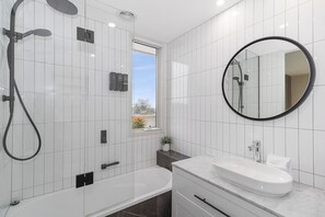 A modern bathroom with a bathtub, a sink, and a shower. - Corner Penthouse with City Views in Armadale (Armadale)