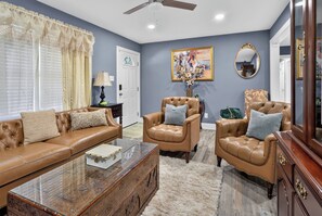 A living room with a brown leather sofa, two armchairs, a glass coffee table, and a decorative wooden chest. -  3-bedrooms in Rocky Mount: 5-15 min. of Event & imperial Ctrs & Sports Complex, (Rocky Mount)