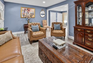 A living room with a brown leather sofa, two leather armchairs, a glass coffee table, and a wooden cabinet. -  3-bedrooms in Rocky Mount: 5-15 min. of Event & imperial Ctrs & Sports Complex, (Rocky Mount)