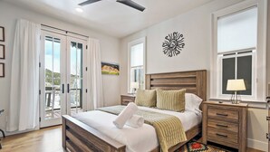 Un dormitorio con una cama de madera, una mesita de noche, una lámpara, un tapete estampado y una obra de arte en la pared.