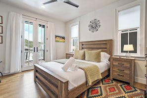 Quarto com cama de madeira, mesa de cabeceira, luminária, tapete estampado e uma obra de arte na parede.