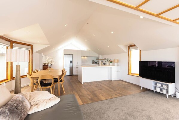 A modern apartment with a dining area, kitchen, living room, and a TV.