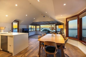 Una cocina moderna con zona de comedor, ventanas amplias y vista al mar.