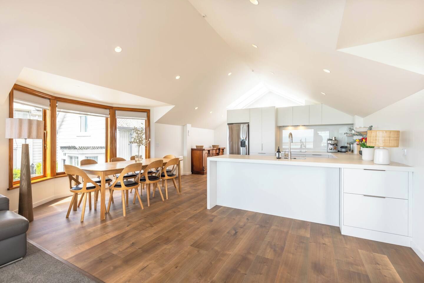 A modern kitchen with a central island, wooden dining table, and chairs.