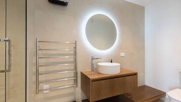 A modern bathroom with a round mirror, a white sink, and a towel rack.