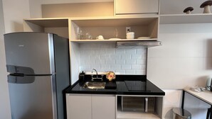 A compact kitchen with a refrigerator, a microwave, a sink, and a stove. - Vrbo Property (São Paulo)