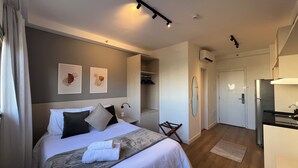 A modern hotel room with a neatly made bed, a walk-in closet, and a kitchenette. - Vrbo Property (São Paulo)