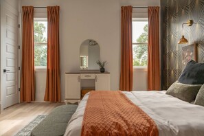 Una camera da letto con un letto, una cassettiera, uno specchio e tende.