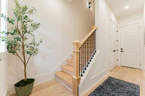 A staircase with wooden steps and black balusters, leading to a white door. - Weekend Getaway-Walk to Coffee Shop- 2 Car Garage! (Nashville)