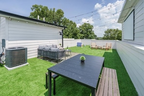 A backyard with a patio table, outdoor furniture, and a lawn. - Getaway! Walk to Coffee and Food -2 Car Garage! (Nashville)