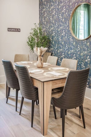 A dining area with a wooden table, six chairs, and a vase with dried plants. - Getaway! Walk to Coffee and Food -2 Car Garage! (Nashville)