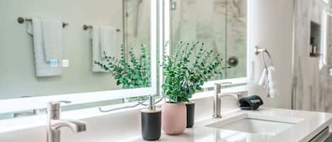 Un baño moderno con dos lavamanos, un espejo grande y plantas en macetas.
