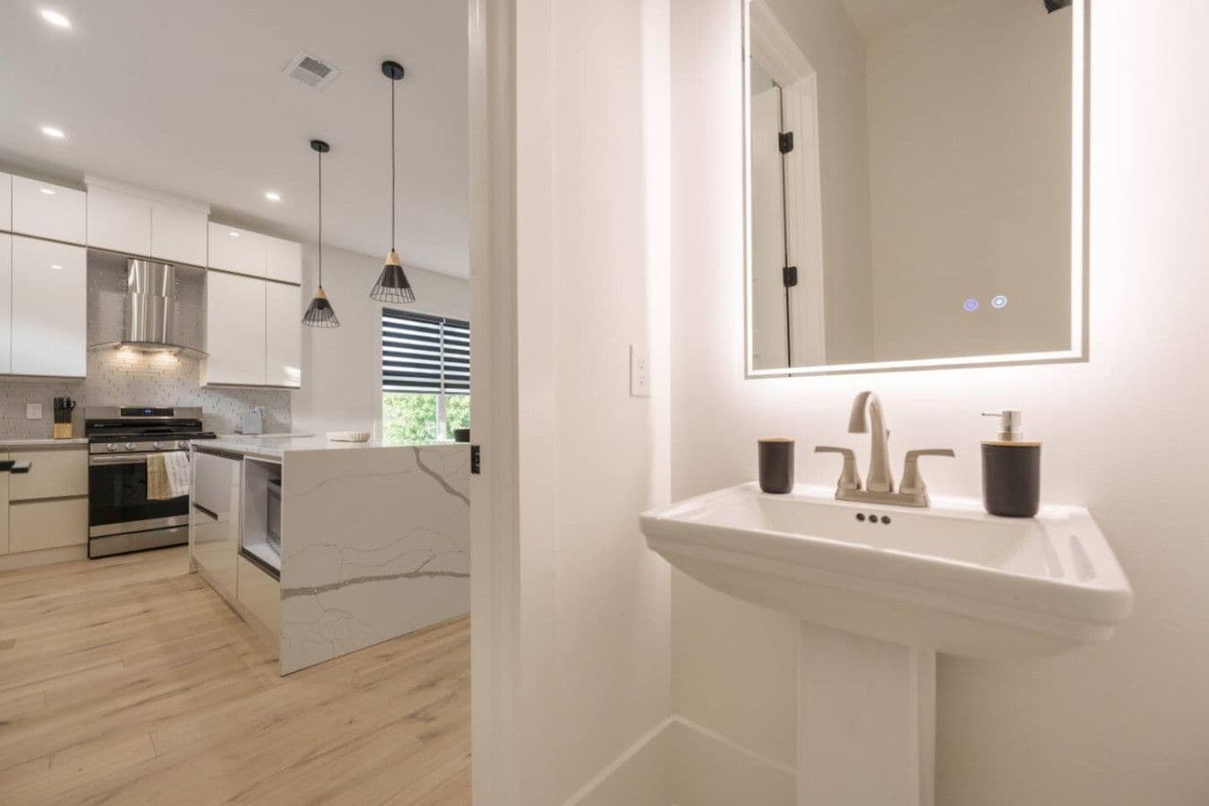 A modern kitchen with white cabinetry, a central island, and pendant lighting.