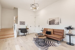 A living room with a sofa, a coffee table, a zebra rug, a desk with a chair, and a staircase. - 2 Bedroom - Workspace/Fast WiFi - 2 Car Garage! (Nashville)