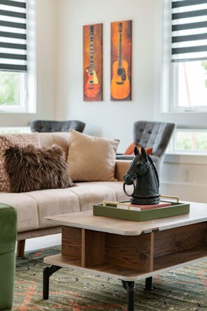 A living room with a sofa, a coffee table with a horse figurine, and two paintings on the wall. - 2 Bedroom - Workspace/Fast WiFi - 2 Car Garage! (Nashville)