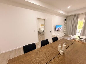A modern dining area with a wooden table, black chairs, and a television mounted on the wall. - 1-Bed Apt. Heart of Oranjestad CasaAmarilla203 (Oranjestad)