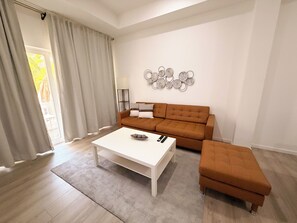 A modern living room with a sofa, a coffee table, and a decorative wall piece. - 1-Bed Apt. Heart of Oranjestad CasaAmarilla203 (Oranjestad)