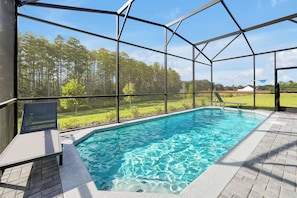 A swimming pool with a clear view of the surrounding landscape, including trees and a distant building. - Dream Family Escape, Pool and Themed Rooms (Clermont)