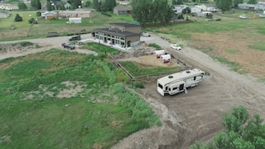 Vista aérea de una zona residencial con una casa moderna, un camino de tierra y una caravana estacionada cerca.