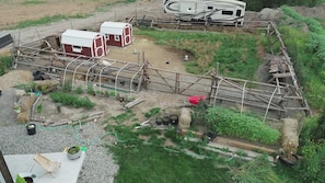 Propiedad rural con área cercada, un edificio rojo y blanco y un remolque.