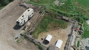 Vista aérea de un camping con una caravana, una zona vallada y un pequeño edificio.
