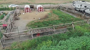 A fenced outdoor area with two red and white sheds, a wooden structure, and a parked RV.