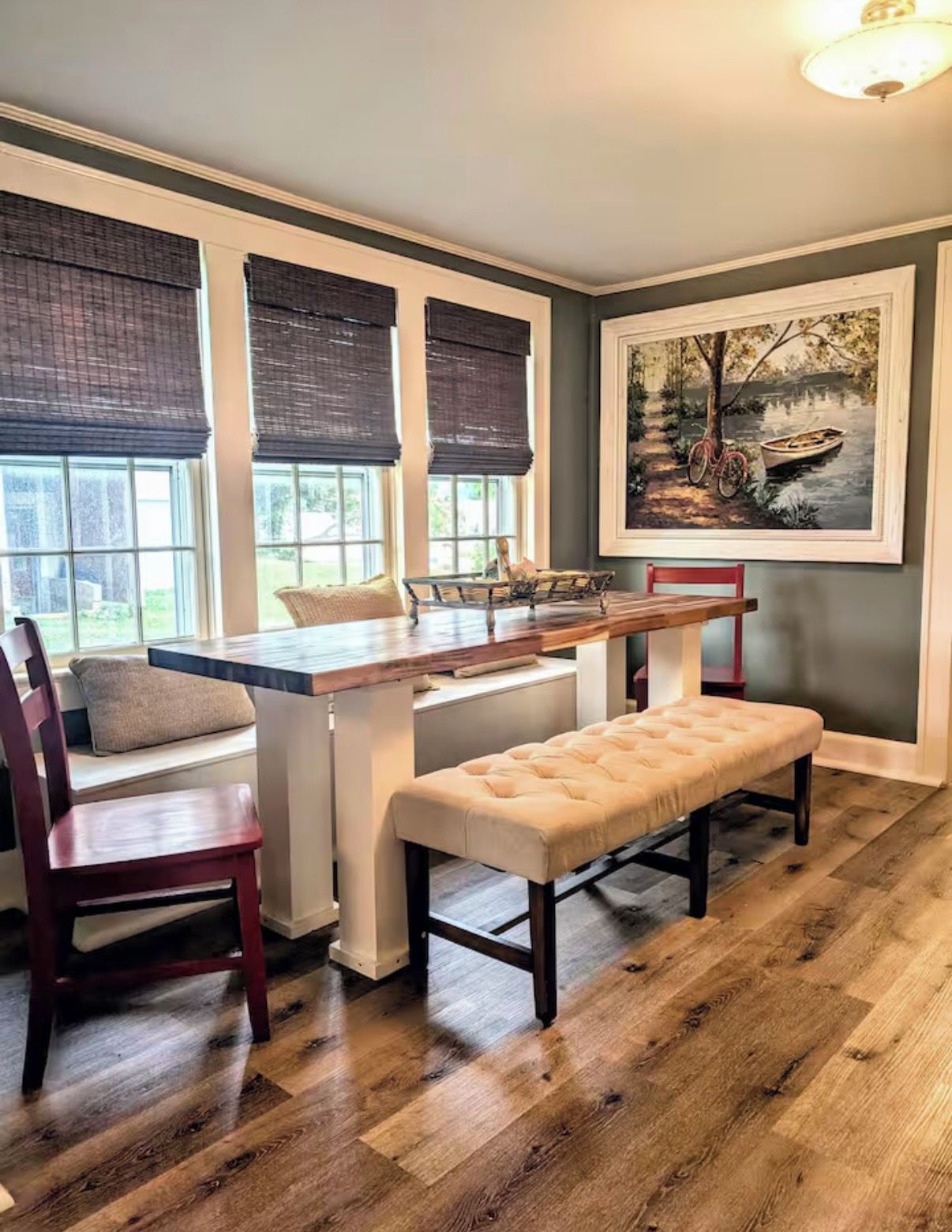 A dining area with a wooden table, two chairs, a bench, and a window with blinds.