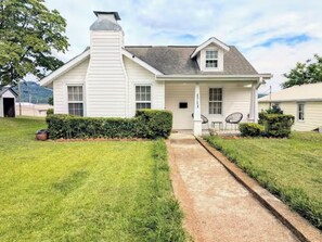 A single-story house with a front porch, a chimney, and a small garden area. - Cozy Cottage Near Lake & Downtown Guntersville (Guntersville)