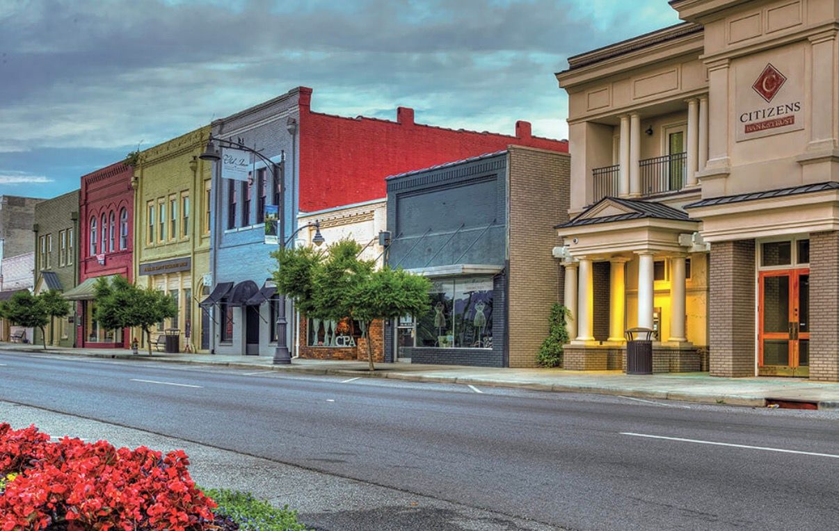 A street with various buildings, including a bank and a hotel with a classical facade.