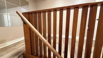 A wooden staircase with a handrail, leading to a room with a white door and a tiled wall.