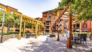 Un espace extérieur aménagé en terrasse, avec des pergolas en bois, un sol en pierre et des sièges d’extérieur.