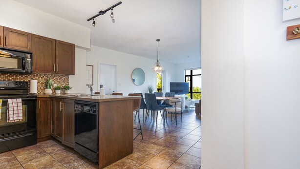 Une cuisine moderne avec des meubles de couleur bois foncé, un four encastré et un îlot central.