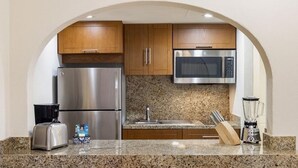 A kitchen with stainless steel appliances, wooden cabinets, granite countertops, a toaster, a blender, and a knife block. - Luxurious 1-bedroom 1 bath apartment in the heart of Loreto (Ensenada)