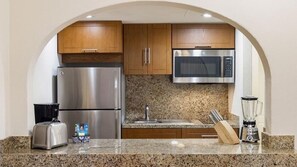 Cucina con elettrodomestici in acciaio inossidabile, mobili in legno, piani in granito, un tostapane, un frullatore e un portachiodi.