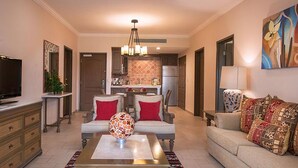 A living room with a sofa, armchairs, a coffee table, and a TV. - Luxurious 1-bedroom 1 bath apartment in the heart of Loreto (Ensenada)
