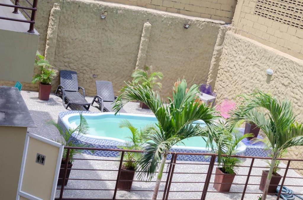 A rooftop pool area with lounge chairs, potted plants, and a small hot tub.
