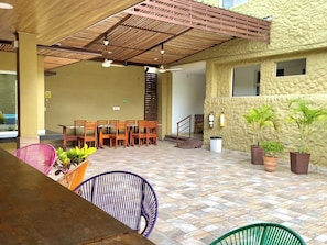 An outdoor seating area with wooden tables and chairs, potted plants, and a tiled floor. - Hotel Sofichic by Caribecheap (Barranquilla)