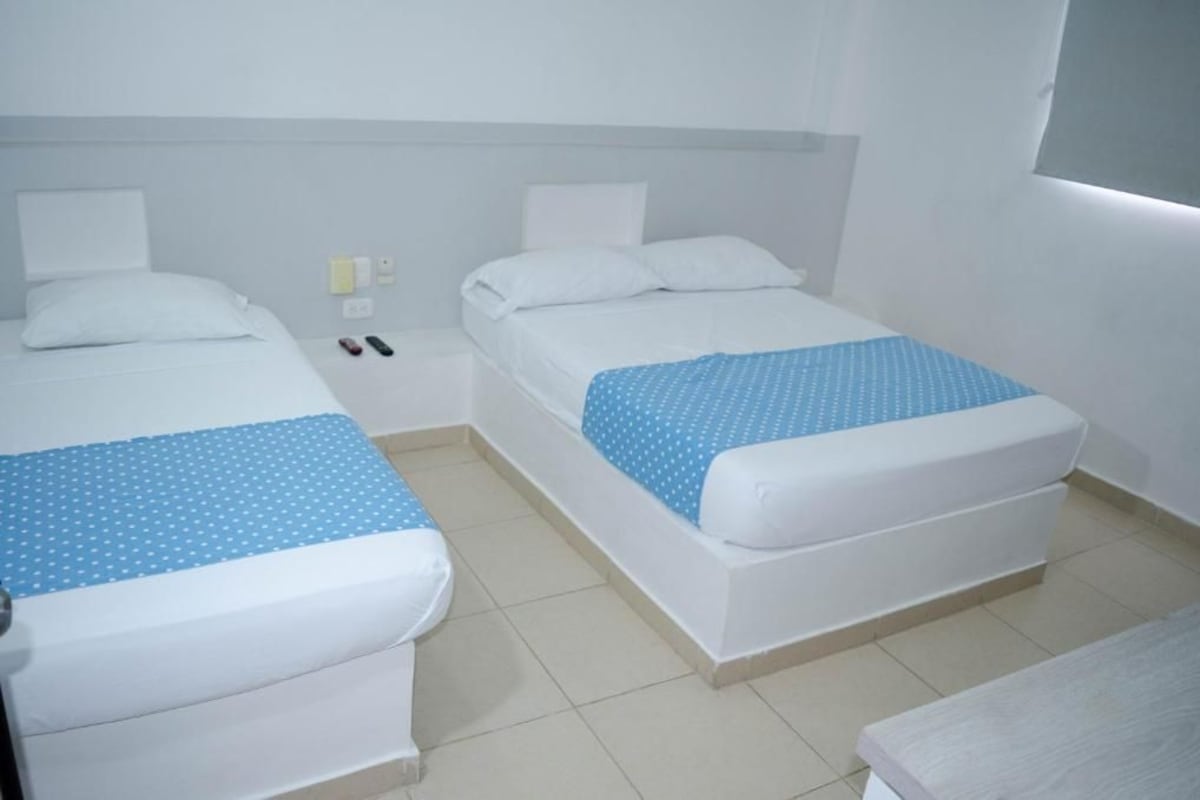A hotel room with two single beds, each with a white mattress and blue polka dot bedspread.