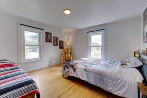 Ein Schlafzimmer mit zwei Betten, einem Holzstuhl und Bildern an den Wänden.