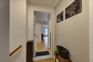 Un pasillo con una puerta de madera, una alfombra oscura y un cartel en la pared.
