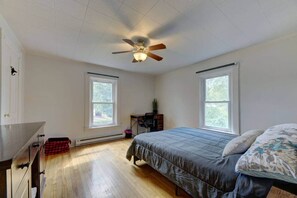 Un dormitorio con cama, escritorio y ventilador de techo.