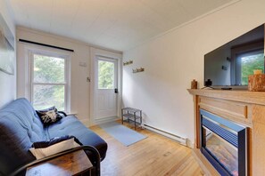 Ein gemütliches Wohnzimmer mit einer Couch, einem Kamin und einem Fernseher.