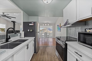 A modern kitchen with a central island, stainless steel appliances, and a view to the outside. - Secret Getaway/Sleeps 5/Hot Tub/Secluded/Lake View (Wofford Heights)