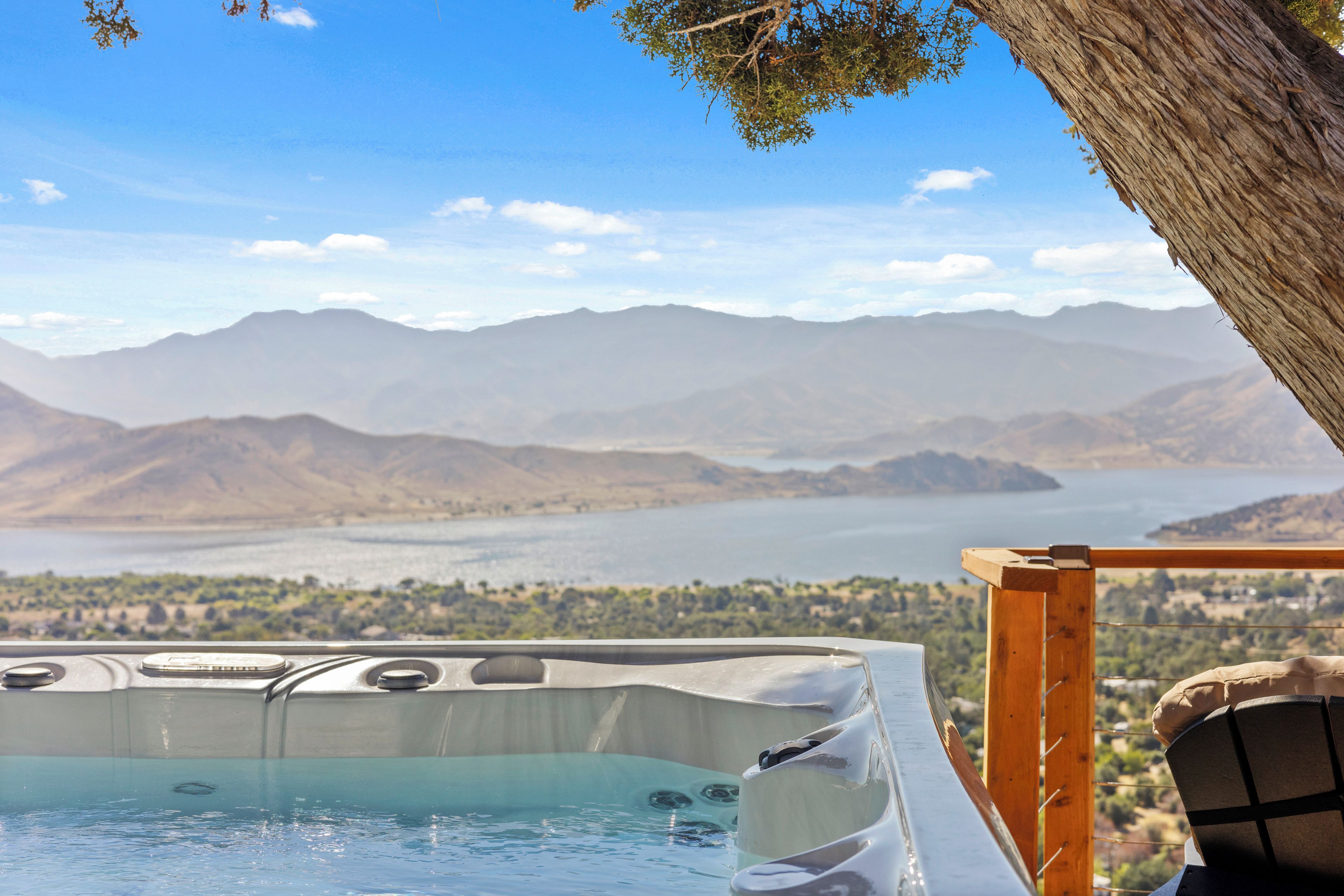 A hot tub with a mountain view, a wooden deck, and a clear sky.