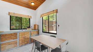 Une cuisine dotée d’un plan de travail en bois, d’un évier et d’un coin repas avec des chaises.