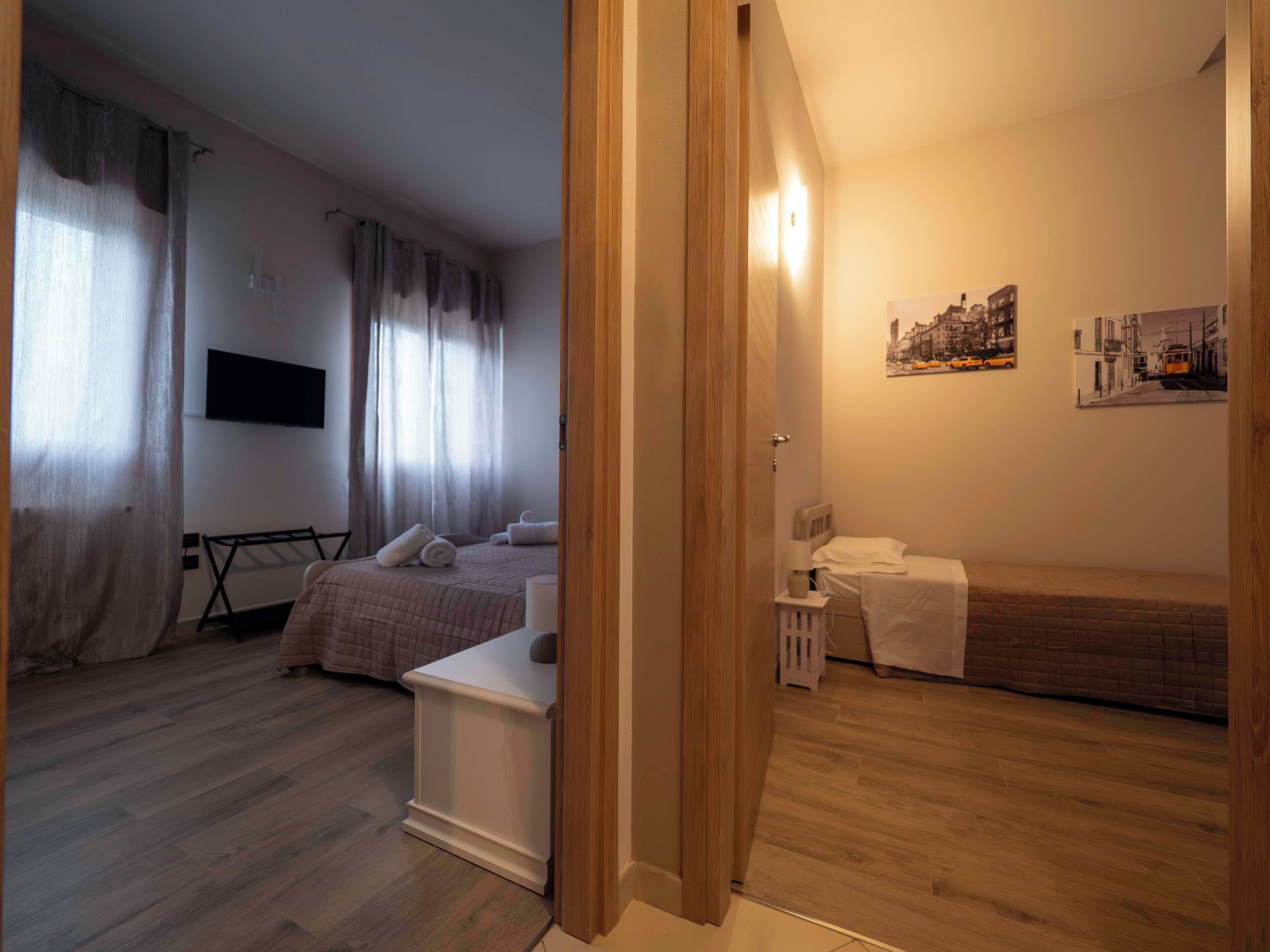 Habitació d'hotel amb llit, taula de nit i televisió penjada a la paret.
